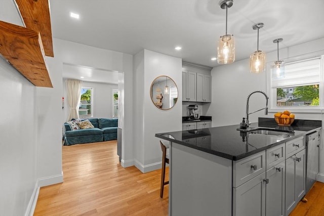 100 Ashland St, Lynn, MA 01905 - kitchen featuring light wood finished floors, gray cabinets, stainless steel dishwasher, dark stone counters, and hanging light fixtures