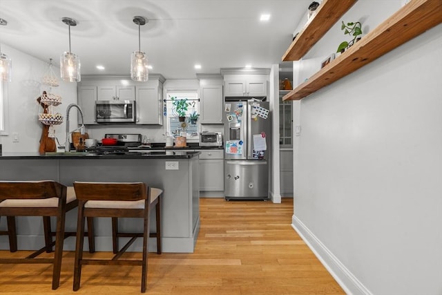 100 Ashland St, Lynn, MA 01905 - kitchen featuring appliances with stainless steel finishes, a kitchen breakfast bar, dark countertops, light wood-type flooring, and pendant lighting