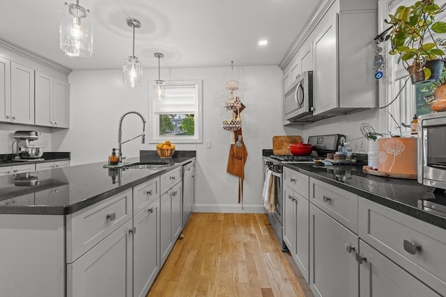 100 Ashland St, Lynn, MA 01905 - kitchen with stainless steel appliances, a peninsula, light wood-style flooring, dark stone counters, and hanging light fixtures
