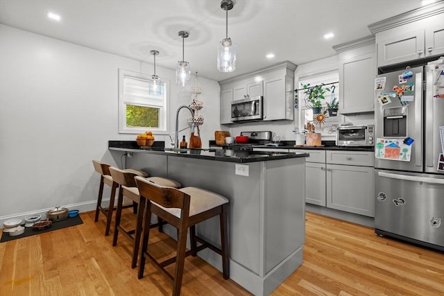100 Ashland St, Lynn, MA 01905 - kitchen featuring appliances with stainless steel finishes, a kitchen bar, dark countertops, light wood finished floors, and pendant lighting