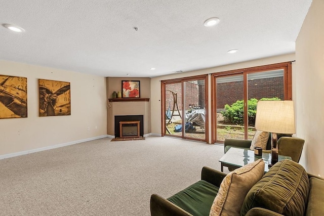 525 Tumbling Hawk Unit 525, Acton, MA 01720 - carpeted living room featuring a fireplace with flush hearth, baseboards, a textured ceiling, and recessed lighting