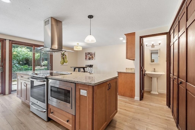525 Tumbling Hawk Unit 525, Acton, MA 01720 - kitchen with island exhaust hood, stainless steel appliances, light wood finished floors, brown cabinets, and a center island