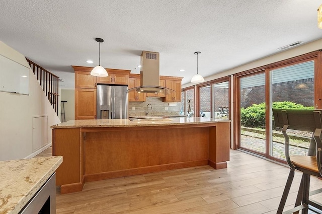 525 Tumbling Hawk Unit 525, Acton, MA 01720 - kitchen with stainless steel refrigerator with ice dispenser, island exhaust hood, light wood-style flooring, tasteful backsplash, and a textured ceiling
