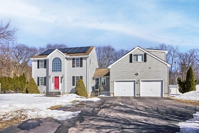 view of front facade featuring a garage, aphalt driveway, and solar panels