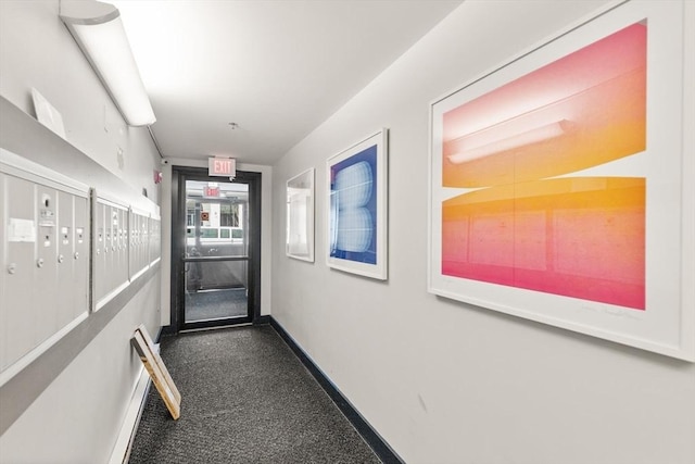 hallway featuring baseboards, carpet flooring, and mail area