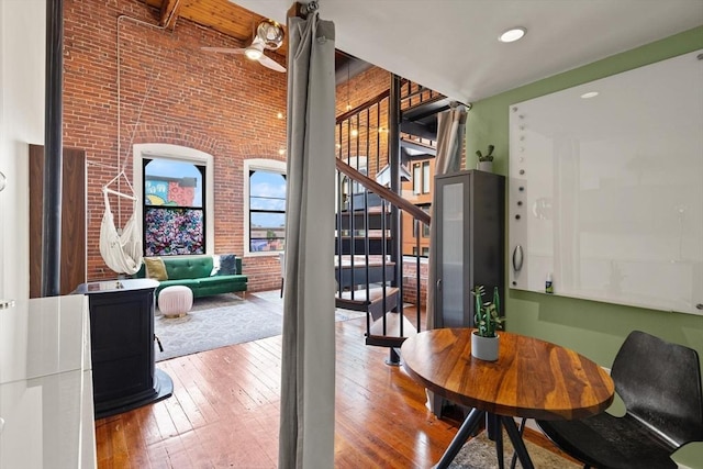 dining area featuring ceiling fan, brick wall, stairway, and hardwood / wood-style flooring