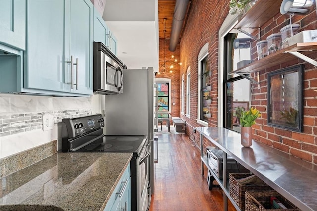 kitchen featuring electric range, brick wall, open shelves, stainless steel microwave, and dark wood-style floors