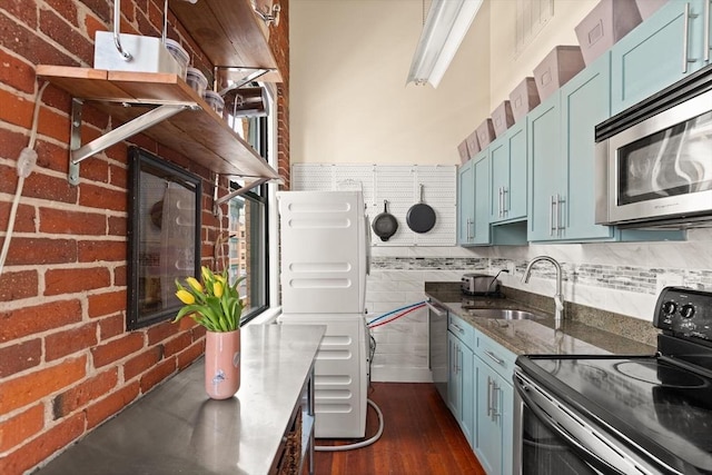 kitchen featuring black electric range, stainless steel microwave, blue cabinets, and a sink