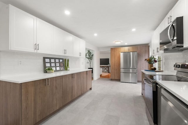 kitchen with stainless steel appliances, white cabinetry, light countertops, light floors, and tasteful backsplash