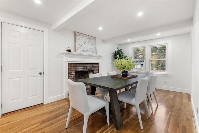 dining room with recessed lighting, a fireplace, light wood-style flooring, and baseboards