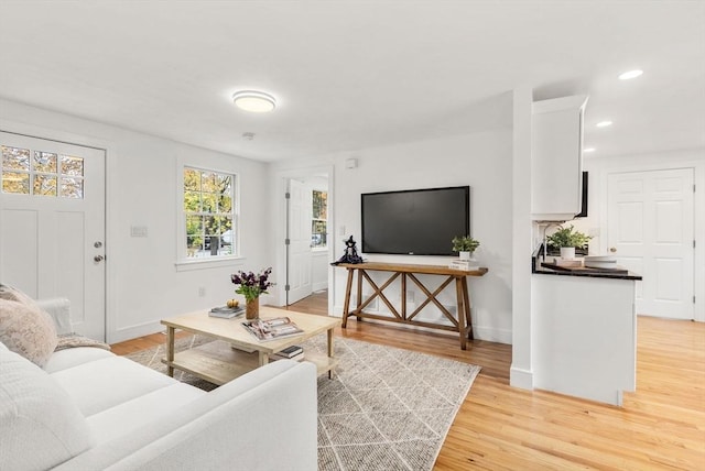 living room featuring baseboards, light wood finished floors, and recessed lighting