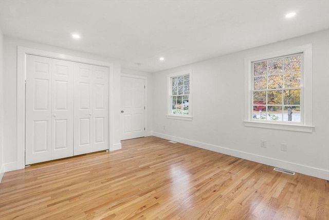 unfurnished bedroom with visible vents, light wood-style flooring, baseboards, and multiple windows