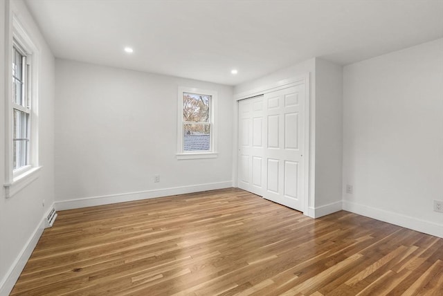 unfurnished bedroom with light wood-type flooring, a closet, baseboards, and recessed lighting