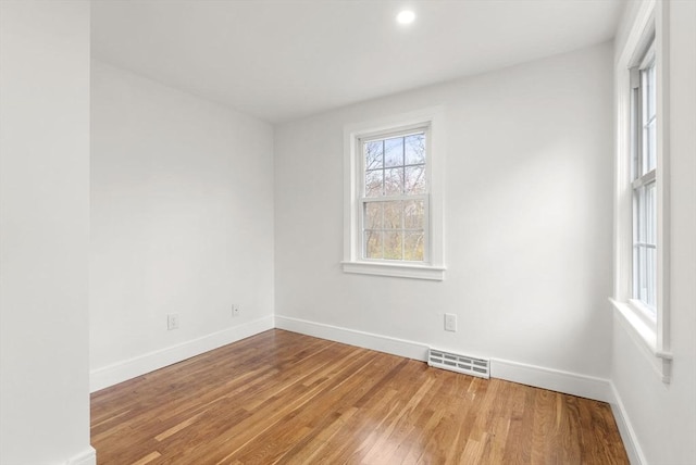 empty room featuring light wood-type flooring, visible vents, and baseboards