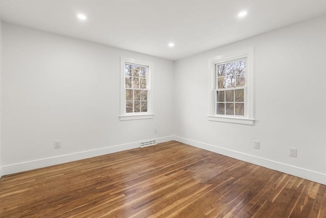 empty room with visible vents, baseboards, and wood finished floors