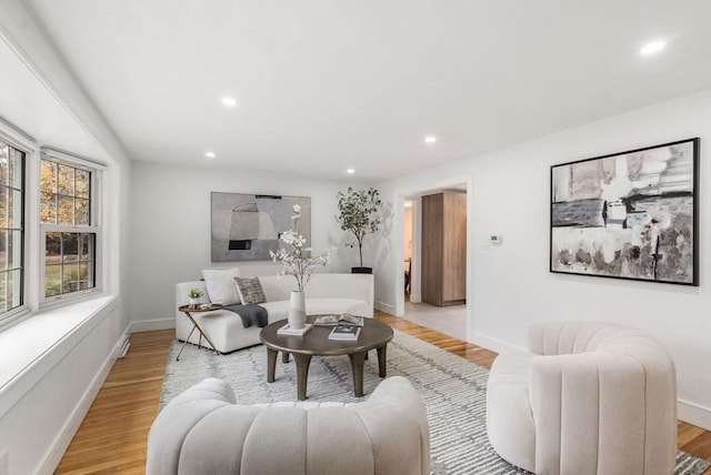 living area with baseboards, light wood finished floors, and recessed lighting