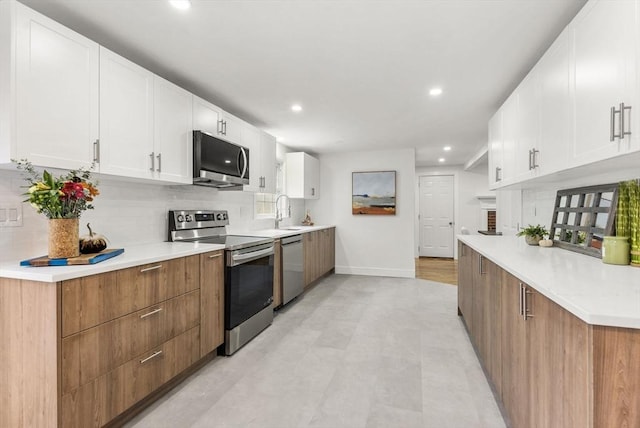 kitchen with white cabinetry, appliances with stainless steel finishes, decorative backsplash, and light countertops