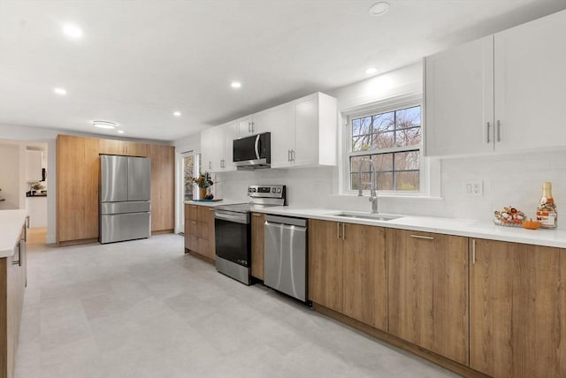 kitchen with white cabinetry, appliances with stainless steel finishes, backsplash, and a sink