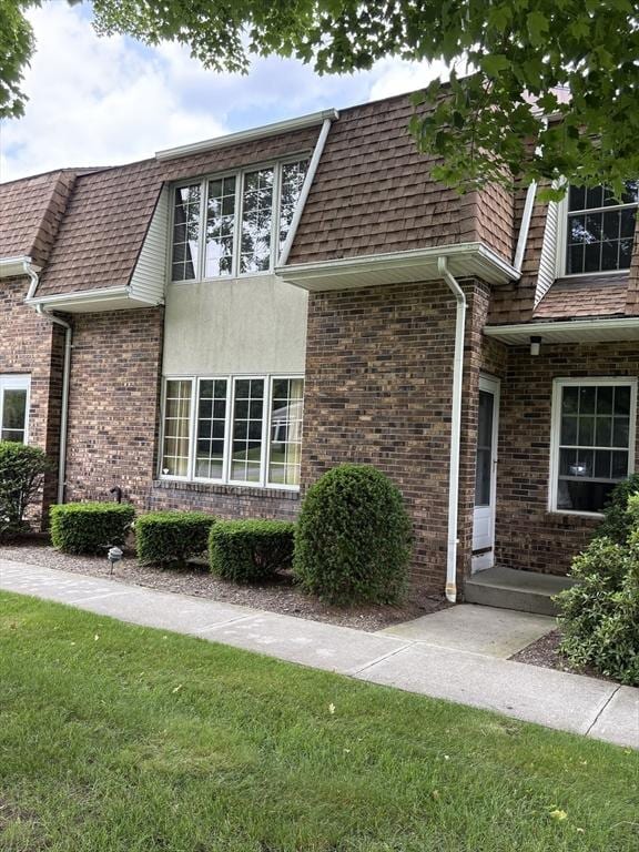 351-355 Main St Unit G, Easthampton, MA 01027 - view of side of home featuring a lawn, roof with shingles, brick siding, and mansard roof