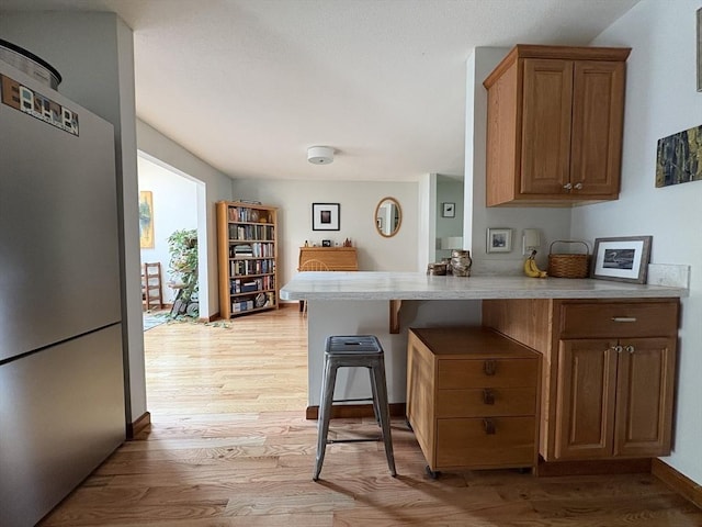 351-355 Main St Unit G, Easthampton, MA 01027 - kitchen with light wood-type flooring, light countertops, a peninsula, and a kitchen breakfast bar