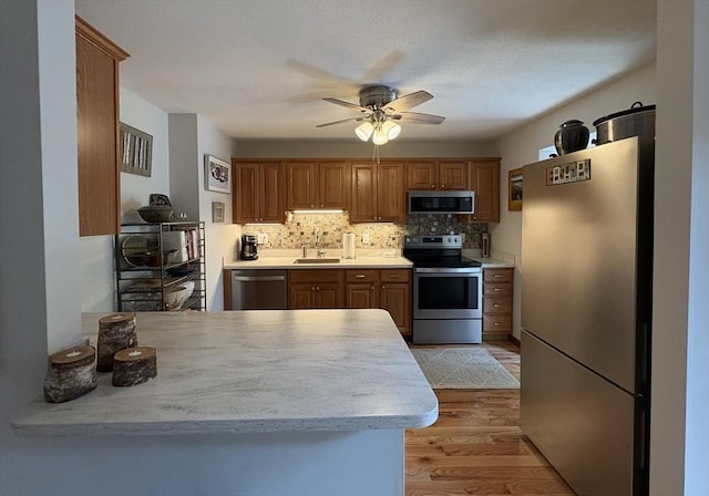351-355 Main St Unit G, Easthampton, MA 01027 - kitchen with appliances with stainless steel finishes, light countertops, ceiling fan, light wood-type flooring, and brown cabinets