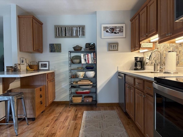 351-355 Main St Unit G, Easthampton, MA 01027 - kitchen with appliances with stainless steel finishes, light wood-type flooring, light countertops, tasteful backsplash, and a peninsula
