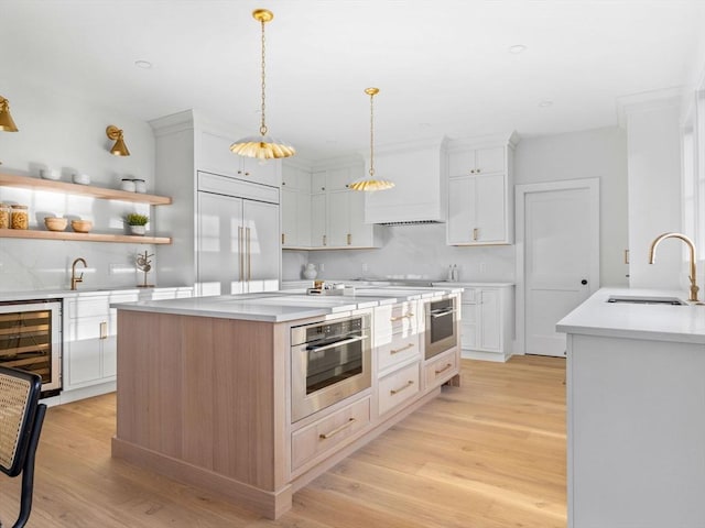 kitchen featuring sink, a kitchen island, oven, paneled built in refrigerator, and white cabinets