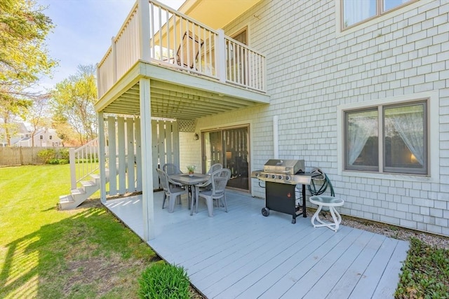 wooden deck featuring fence, outdoor dining space, a yard, and a grill