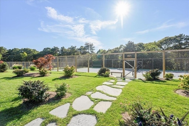 view of yard featuring fence and a tennis court