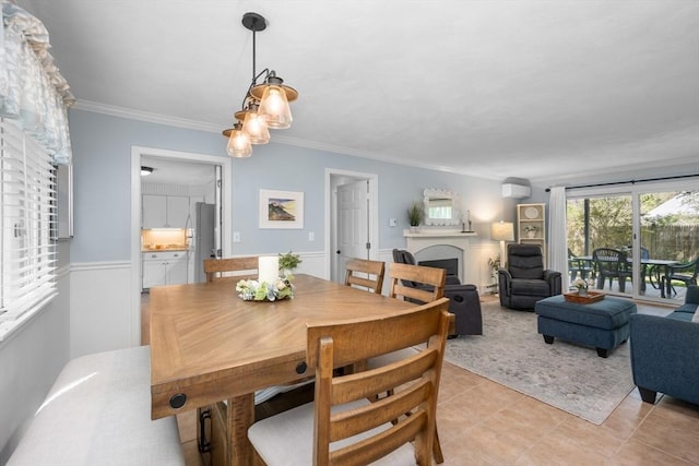 dining room featuring ornamental molding, wainscoting, light tile patterned flooring, and a fireplace
