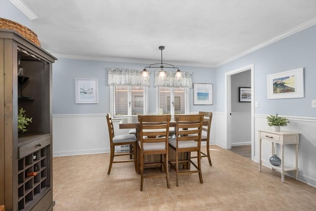 dining room featuring ornamental molding, light tile patterned floors, and a wainscoted wall