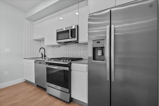 277 Border St Unit 502, Boston, MA 02128 - kitchen with appliances with stainless steel finishes, a sink, white cabinetry, and backsplash