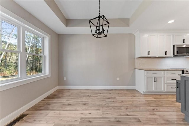 6 Nicols Way Unit 6, Easthampton, MA 01027 - kitchen with stainless steel microwave, a chandelier, a tray ceiling, white cabinetry, and light wood-style floors