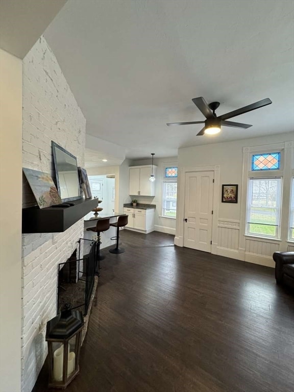 living room with ceiling fan, a healthy amount of sunlight, and dark hardwood / wood-style flooring