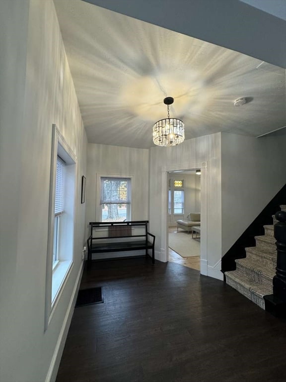 foyer entrance with a chandelier and dark wood-type flooring