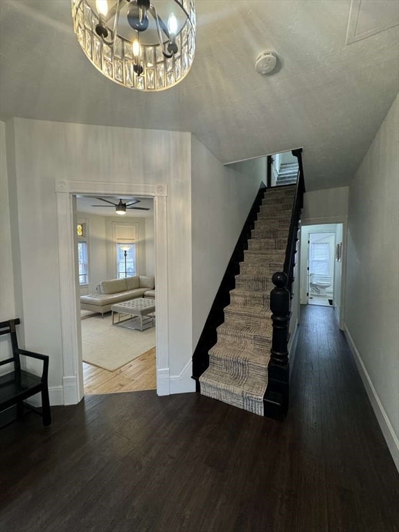 staircase featuring a textured ceiling, wood-type flooring, and ceiling fan