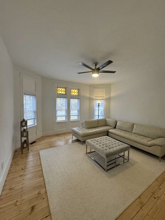 unfurnished living room with ceiling fan, a wealth of natural light, and light wood-type flooring