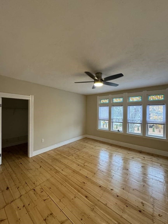 unfurnished room with light hardwood / wood-style flooring, a healthy amount of sunlight, and ceiling fan