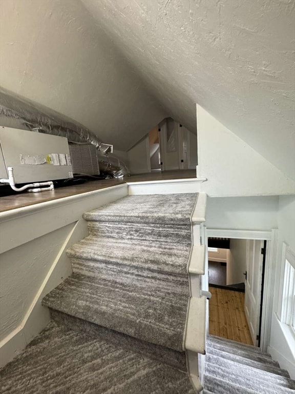 stairway featuring hardwood / wood-style floors and vaulted ceiling