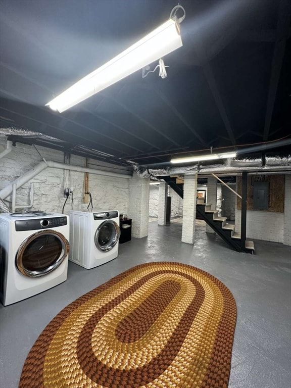 clothes washing area featuring electric panel and washer and clothes dryer