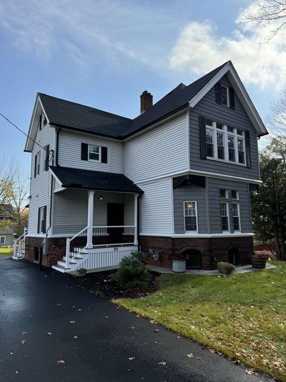 473 Massasoit Rd, Worcester, MA 01604 - traditional-style home featuring a chimney, brick siding, covered porch, a front yard, and aphalt driveway