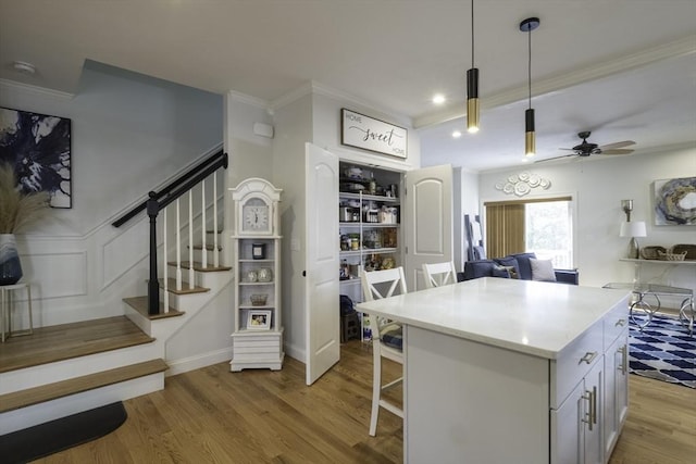 kitchen with a center island, open floor plan, ornamental molding, a breakfast bar, and wood finished floors