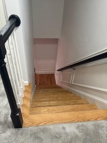 staircase featuring a decorative wall and wainscoting