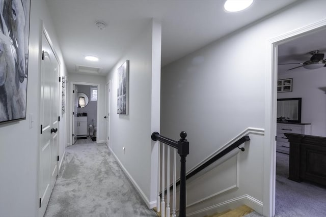 hallway with baseboards, an upstairs landing, and carpet floors