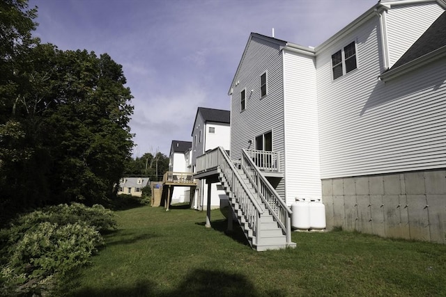 rear view of house featuring a yard, a wooden deck, and stairs