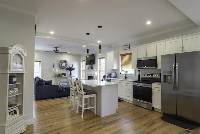 kitchen featuring stainless steel appliances, a fireplace, open floor plan, and white cabinetry