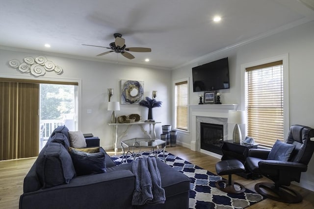 living area featuring plenty of natural light, a ceiling fan, ornamental molding, and wood finished floors