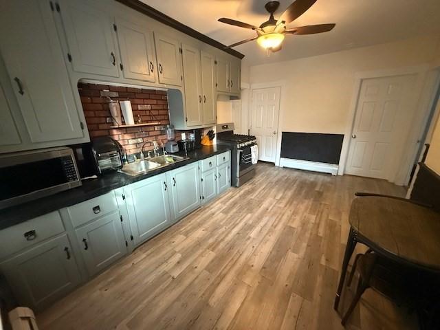 kitchen with ceiling fan, appliances with stainless steel finishes, sink, and light hardwood / wood-style flooring