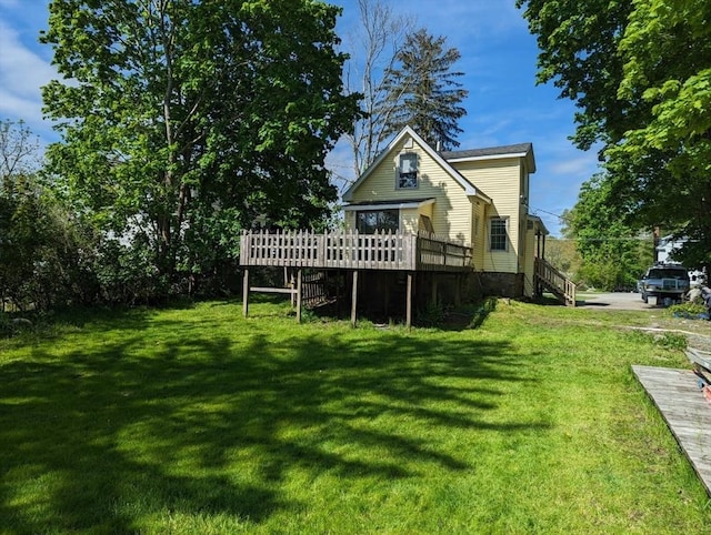 rear view of house featuring a yard, a deck, and stairs