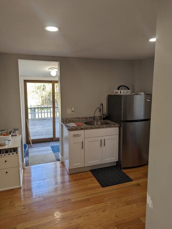 kitchen with a sink, light wood-type flooring, freestanding refrigerator, white cabinetry, and recessed lighting
